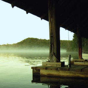 silver flashlight on wooden surface near body of water photo