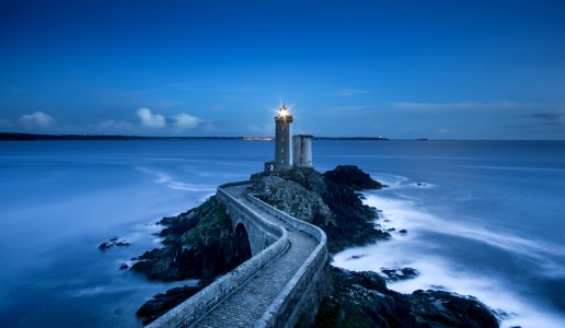 gray lighthouse on islet with concrete pathway at daytime photo