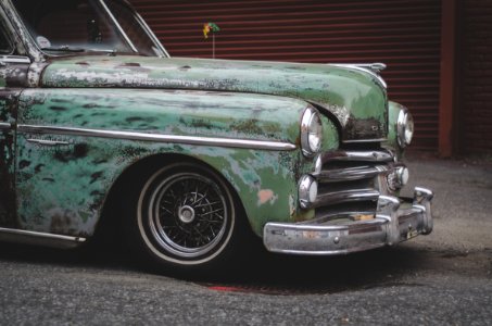 close-up photo of classic green car parked near building photo