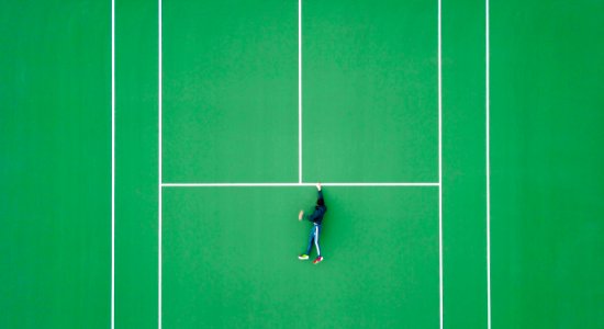 aerial photography of person lying on tennis court