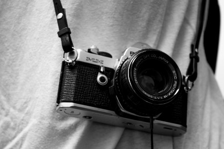 person holding black and gray film camera with sling photo