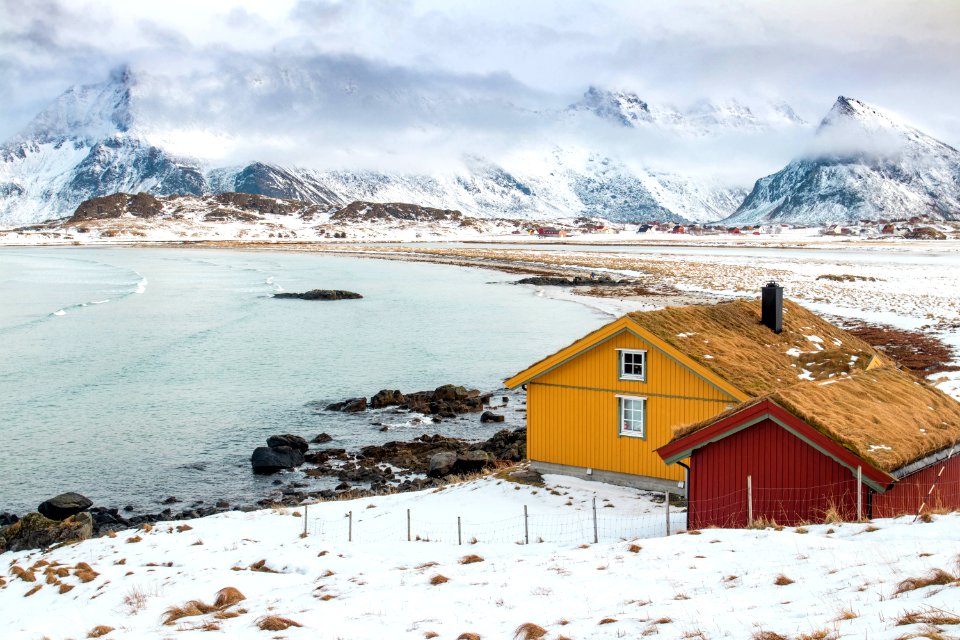 two houses near body of water across hill at daytime