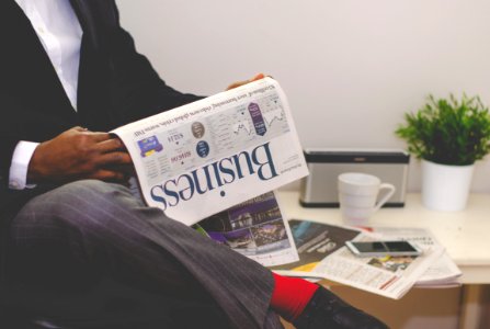 person sitting near table holding newspaper photo
