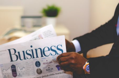 person wearing suit reading business newspaper photo