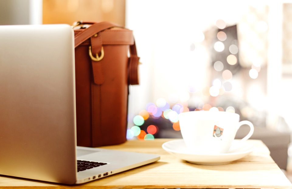 gray laptop beside teacup and bg