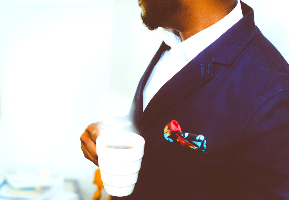 man holding white ceramic mug with coffee photo