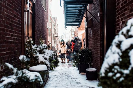 girl standing in between buildings surrounded by plants covered with snow photo