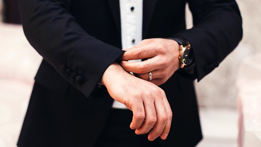 A man's hands adjusting the cuffs of his black suit photo