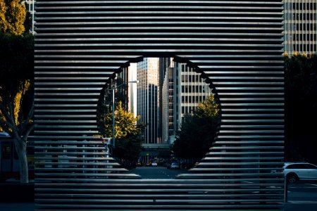 gray concrete building with hole near green trees during daytime photo
