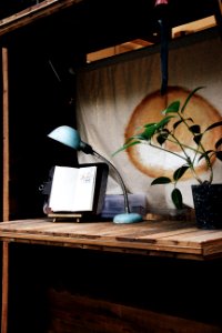 teal study lamp beside black wooden note book with black stand photo