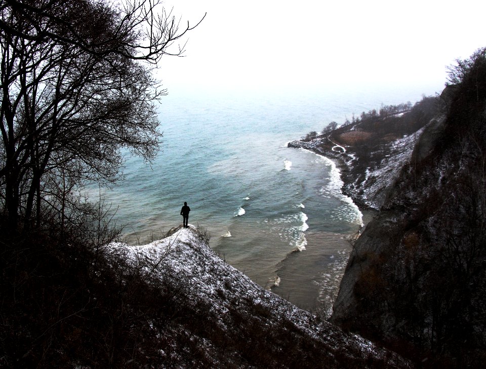 person standing on rock formation near the body of water