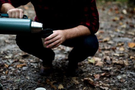 man bending his knees pouring thermal carafe in cup photo