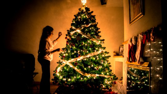 child standing in front of Christmas tree with string lights photo