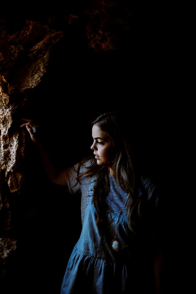 girl wearing blue and white dress holding on brown rocks photo