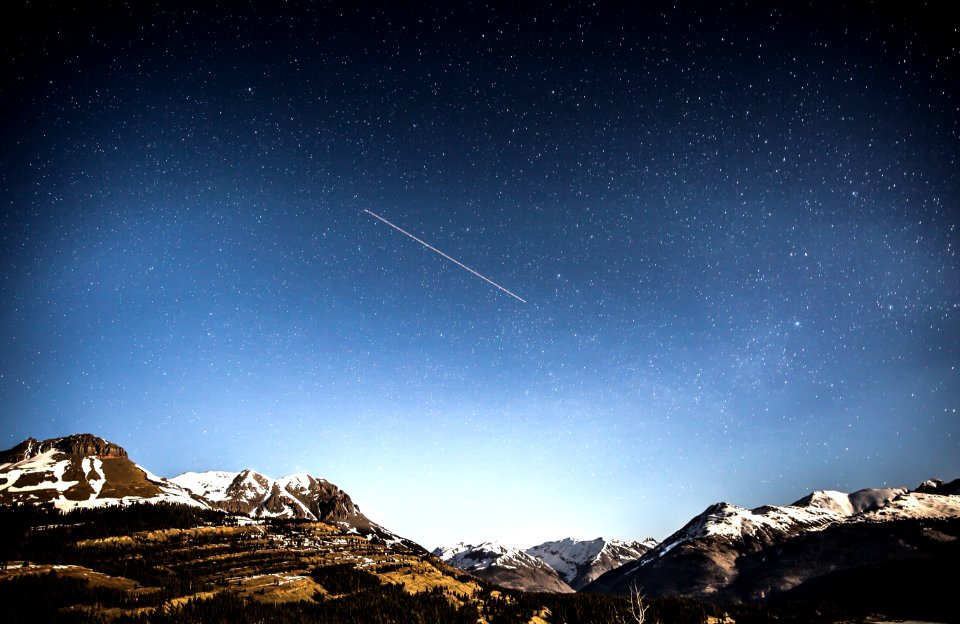 photo of shooting star over snow covered mountains