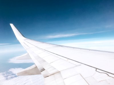 white airplane flying over white clouds
