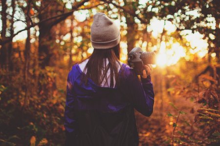woman in forest holding DSLR camera during golden hour photo