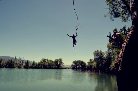 man jumping on body of water with rope photo