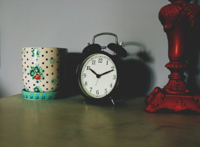 black table clock beside ceramic vase photo