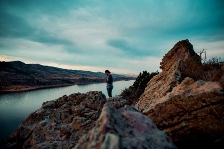 man on brown mountain beside body of water photo