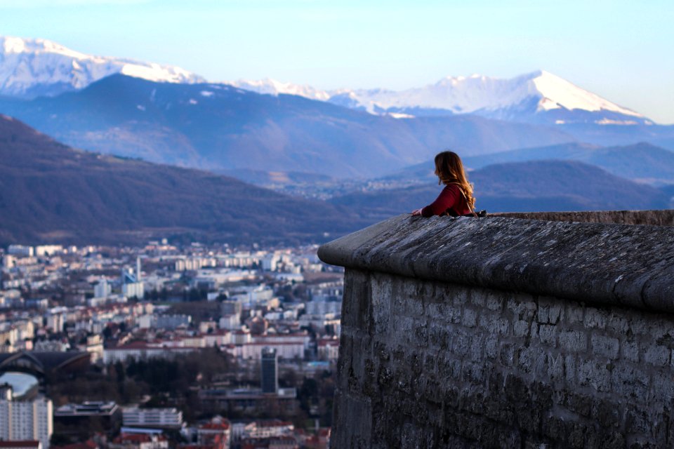 woman standing near high rise buildings and mountains during daytime