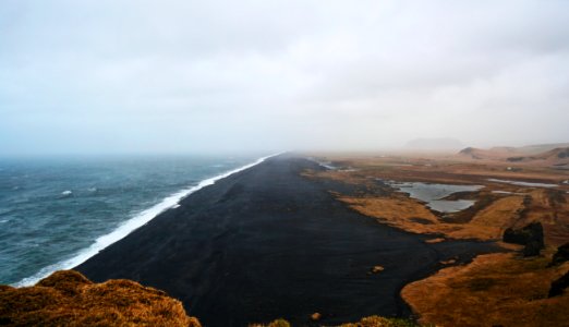 brown and black sand near ocean during daytime photo