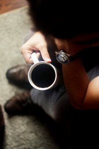 person sitting on couch holding coffee mug photo