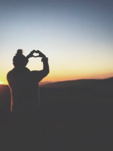 silhouette of a person making heart using her hands photo