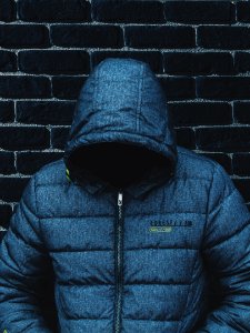 person with head down wearing blue zip-up jacket leaning on wall photo