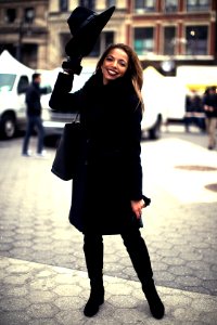 woman wearing black coat standing on gray concrete pavement