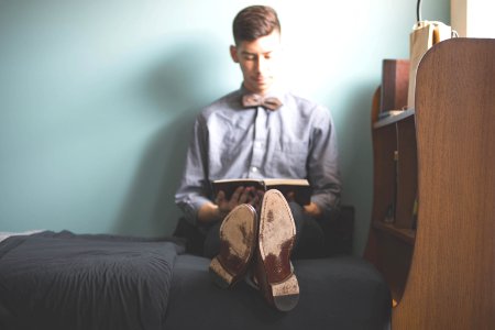 man wearing gray dress shirt reading book