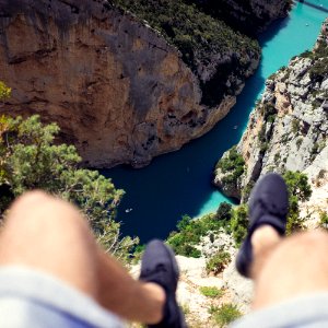 person seating on cliff above body of water photo