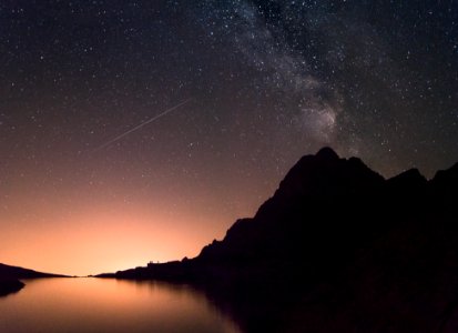 silhouette of mountain beside the body of water at night time