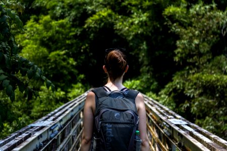 woman wearing backpack walking on bridge