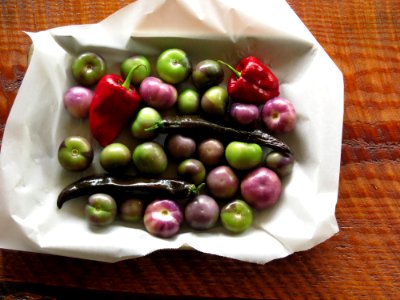 green and purple tomatoes and red bell peppers in white paper photo