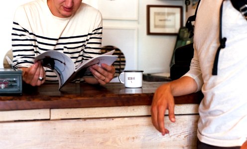 person leaning on table while reading book photo