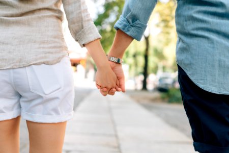 man and woman holding hands together in walkway during daytime photo