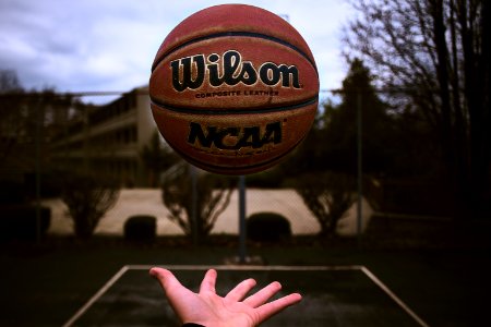 person releasing orange Wilson basketball ball photo