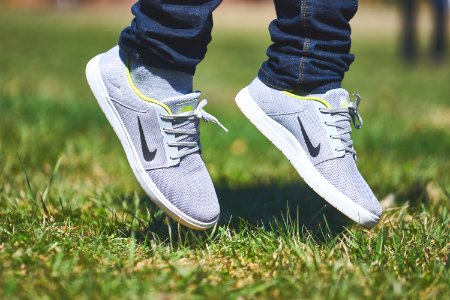 pair of gray Nike low-top sneakers hanging on green grass photo