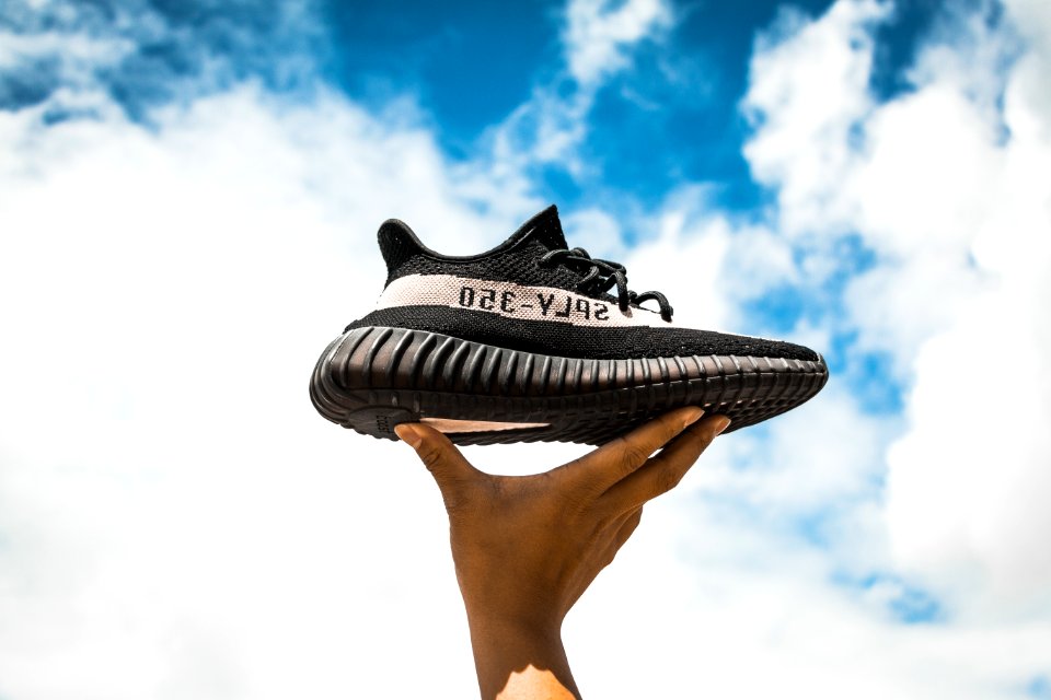 unpaired adidas Yeezy Boost 350 V2 shoe on person's hand