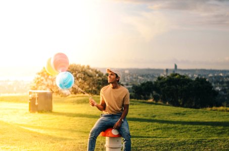 man sitting while holding balloons photo