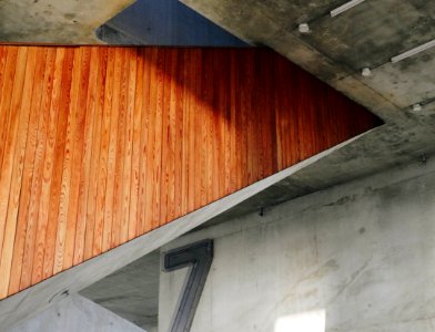 Wooden panelling on the side of a staircase in a building with bare concrete walls photo