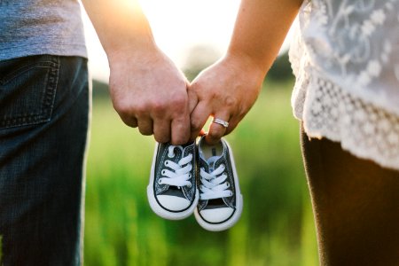 woman and man holding black crib shoes standing near green grass during daytime photo