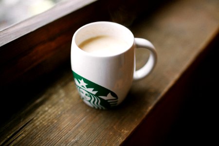 photo of white Starbucks mug on brown wooden surface