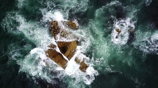 rock formation surrounded by body of water in aerial photography photo