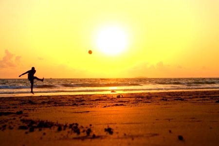 man kicking ball on seashore photo