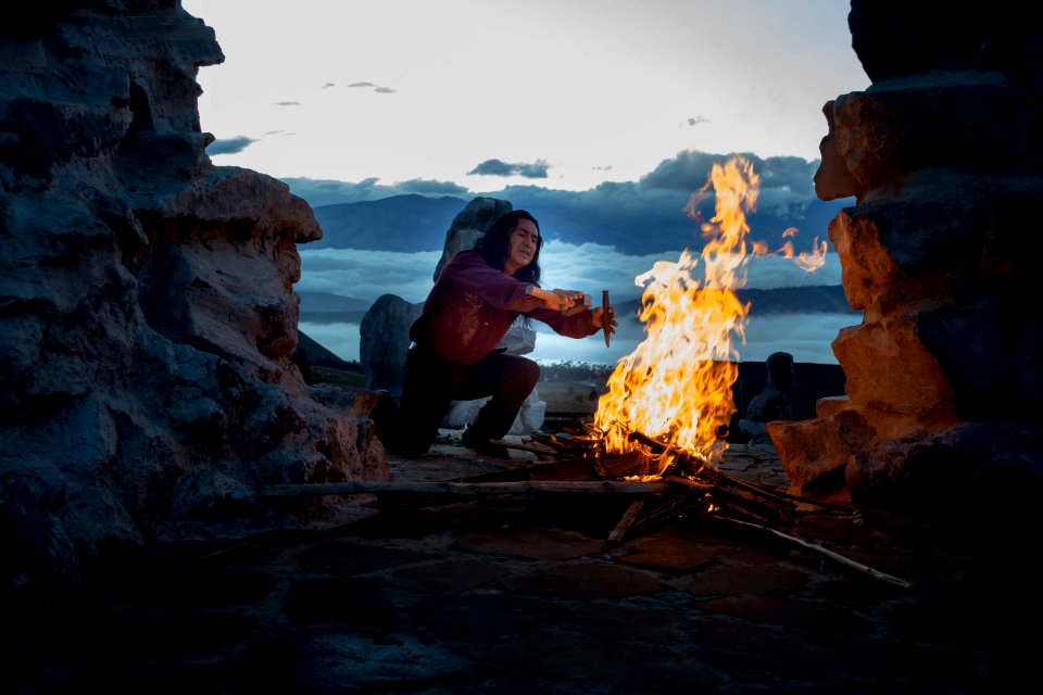 person kneeling in front of bonfire outside