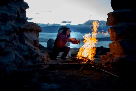 person kneeling in front of bonfire outside photo