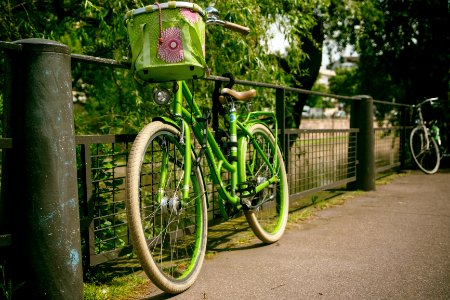 green cruiser bike with basket leaning on gray rail photo