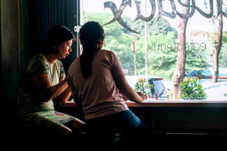women sitting on black wooden stools